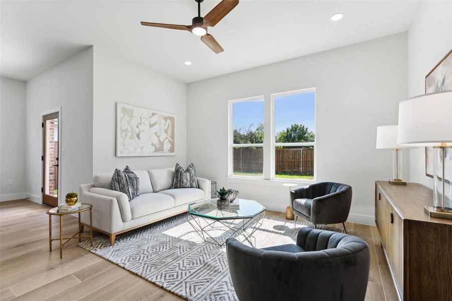 Living room with ceiling fan and light hardwood / wood-style floors