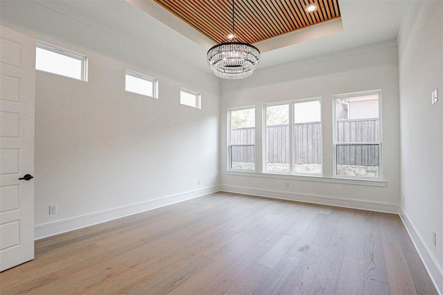 Unfurnished room with light hardwood / wood-style floors, an inviting chandelier, wooden ceiling, and a raised ceiling