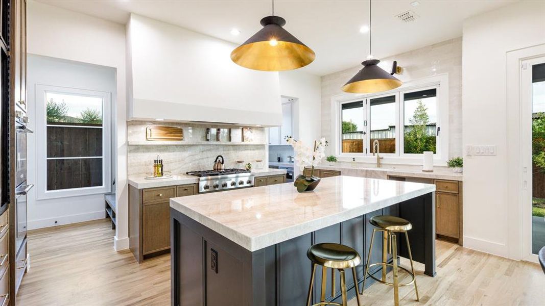 Kitchen featuring a center island, decorative backsplash, light hardwood / wood-style floors, and decorative light fixtures