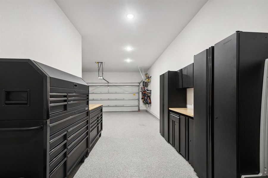 The garage boasts a sleek, modern aesthetic with epoxy floors that gleam under the glow of recessed lighting.