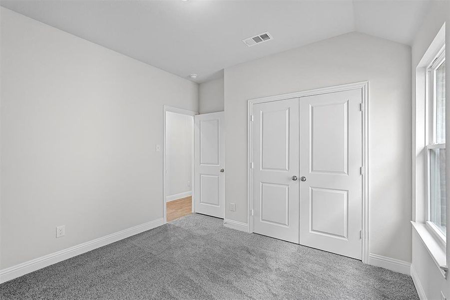 Unfurnished bedroom with carpet floors, a closet, and lofted ceiling