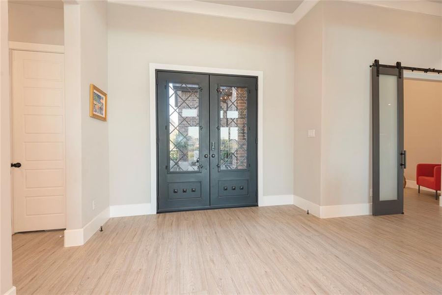 Entrance foyer featuring a barn door, light wood-type flooring, and french doors