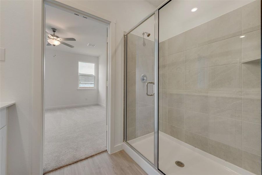 Bathroom featuring a shower with shower door, ceiling fan, hardwood / wood-style floors, and vanity