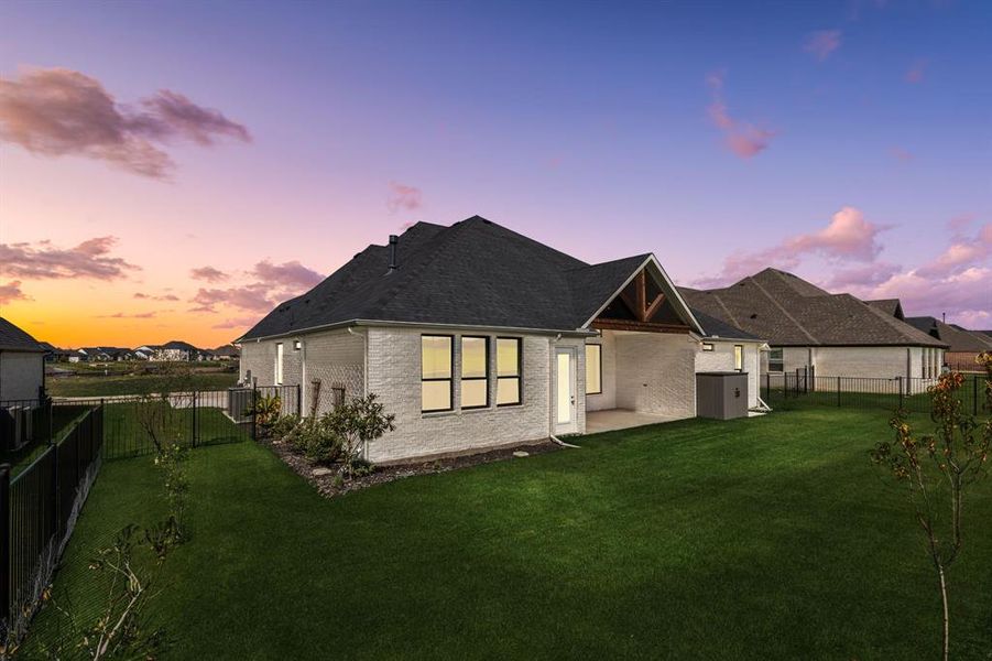 Back house at dusk with a lawn