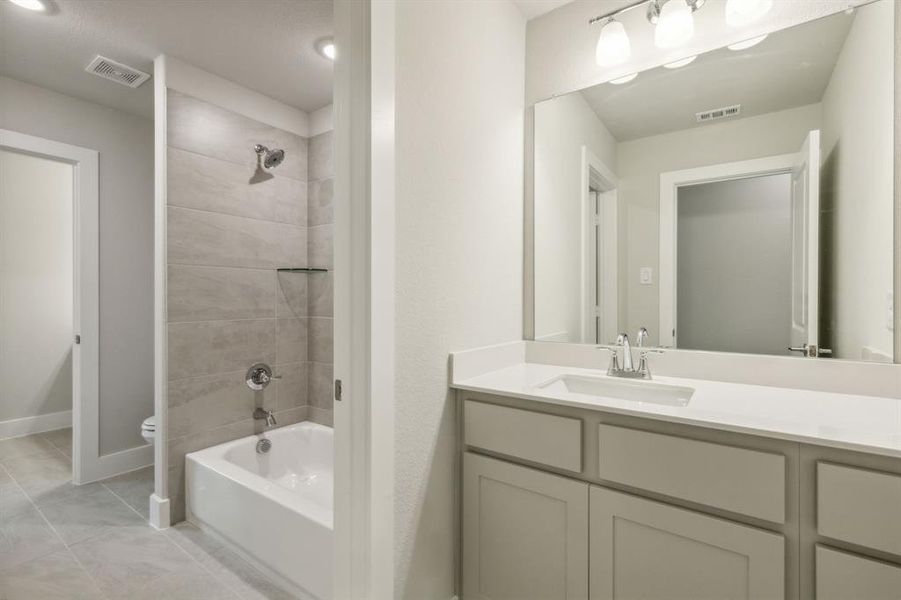 Full bathroom featuring tiled shower / bath combo, vanity, and toilet