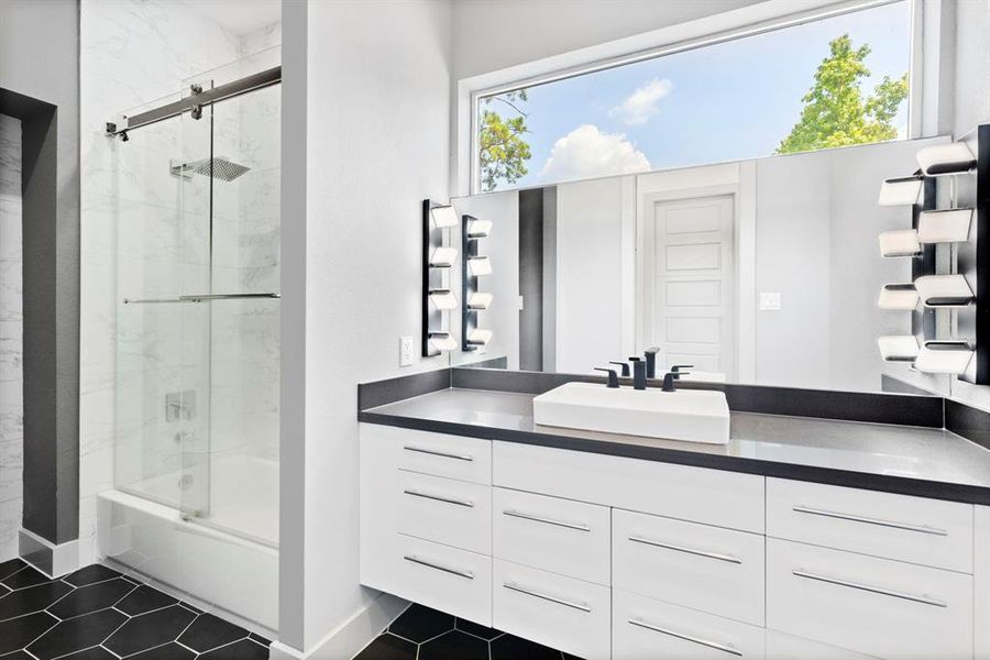 Natural light illuminates this beautiful bath with sliding glass door tub shower combination and a generous vanity.