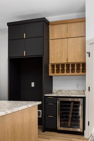 Bar featuring light stone counters, light hardwood / wood-style flooring, and beverage cooler