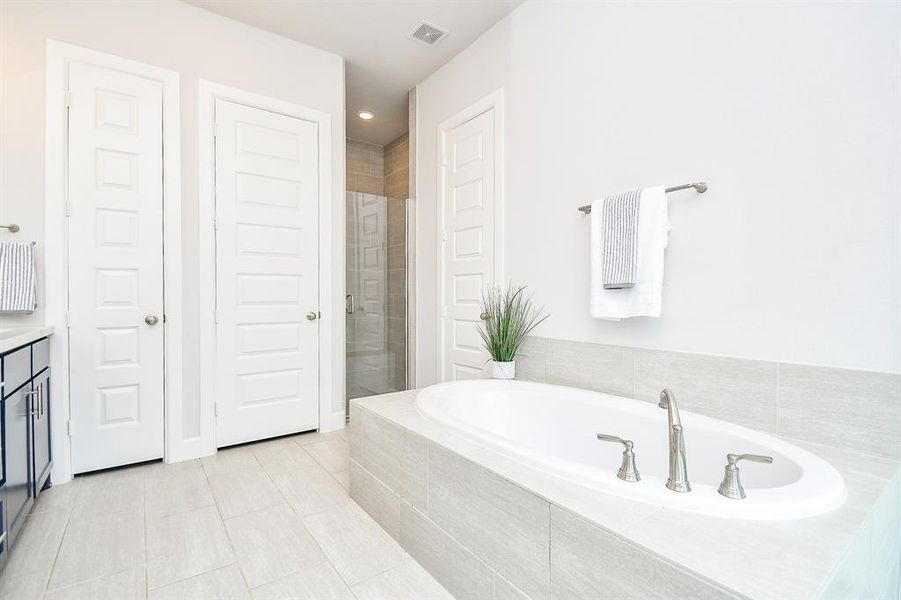 The primary modern, bright bathroom features a large built-in bathtub with tile surround, a separate walk-in shower with glass doors, 2 walk-in closets, 2 separate vanities and separate toilet room