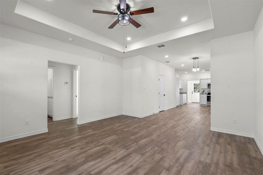 Unfurnished room featuring ceiling fan, a raised ceiling, and dark hardwood / wood-style floors