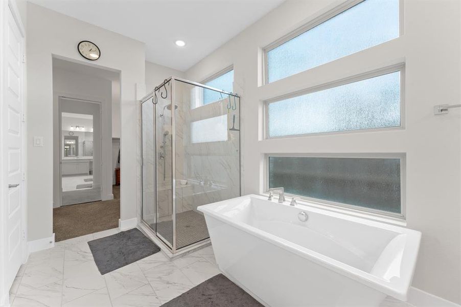 The en suite bathroom features a contemporary design with a separate tub and shower for ultimate relaxation.