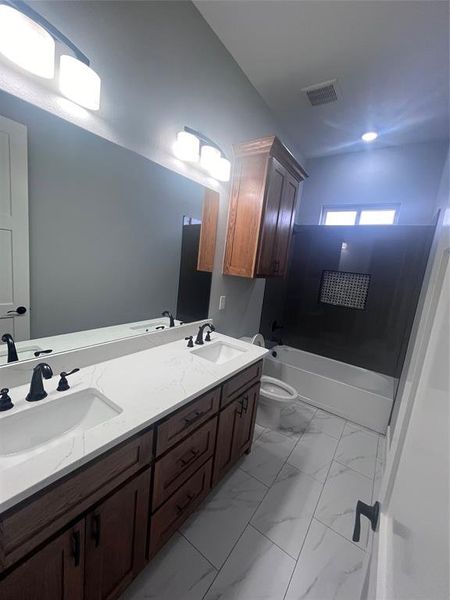 Full bathroom with toilet, vanity, and  shower combination