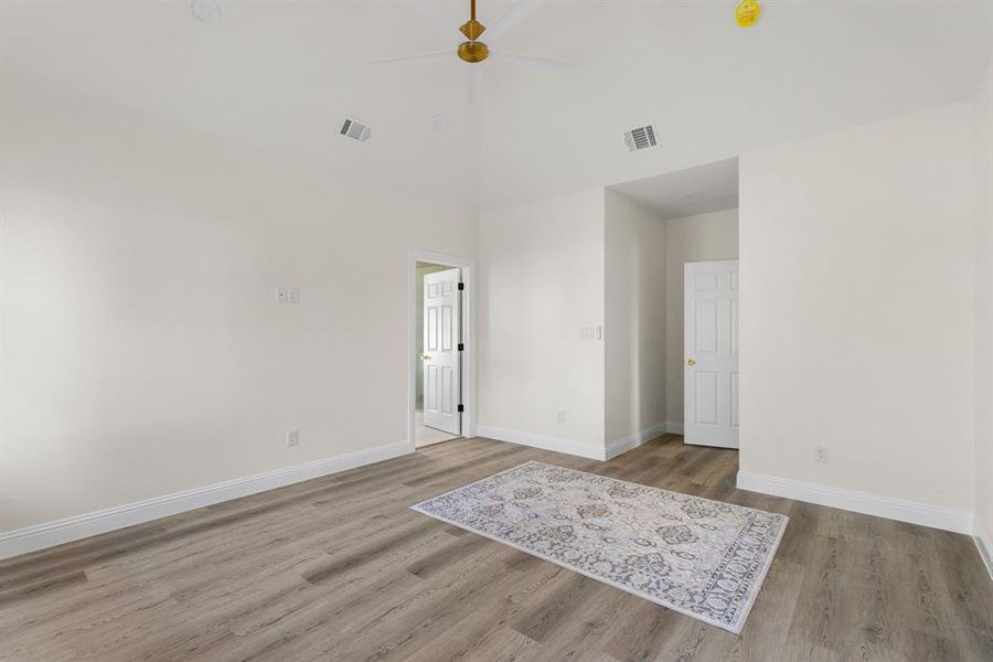 Spare room with ceiling fan, wood-type flooring, and a high ceiling