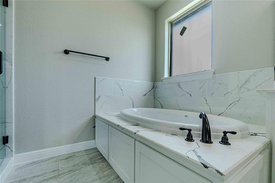 Bathroom featuring tile patterned flooring, a bathtub, and a wealth of natural light