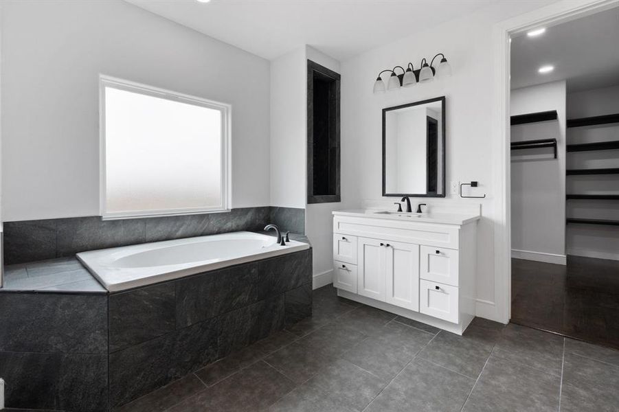 Bathroom with vanity, hardwood / wood-style flooring, and a relaxing tiled tub