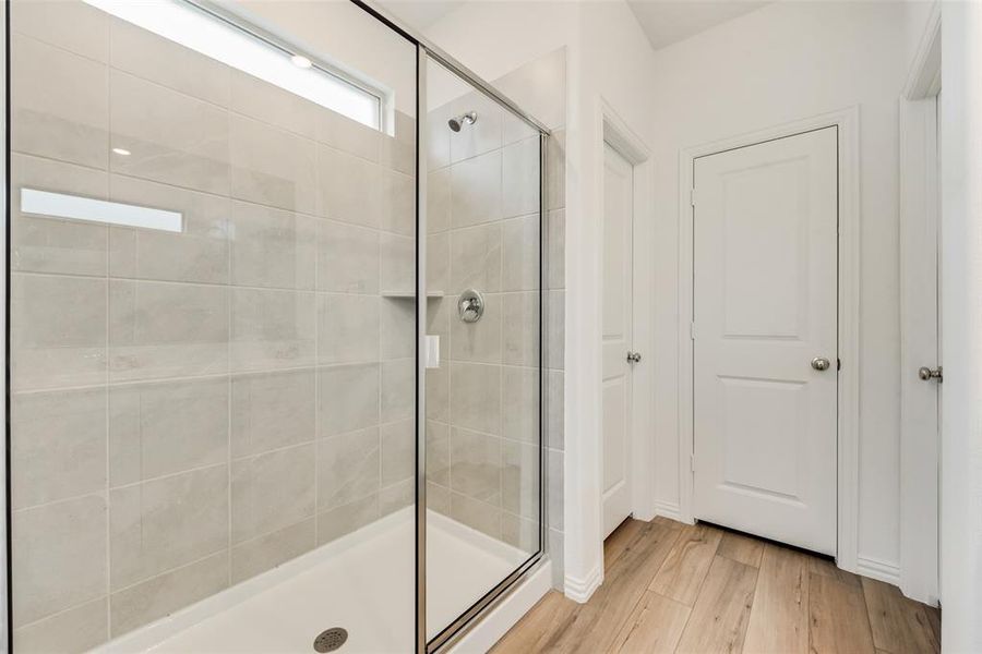 Bathroom featuring hardwood / wood-style flooring and a shower with shower door