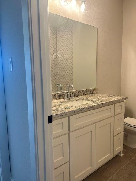 Bathroom featuring vanity, toilet, and tile patterned floors