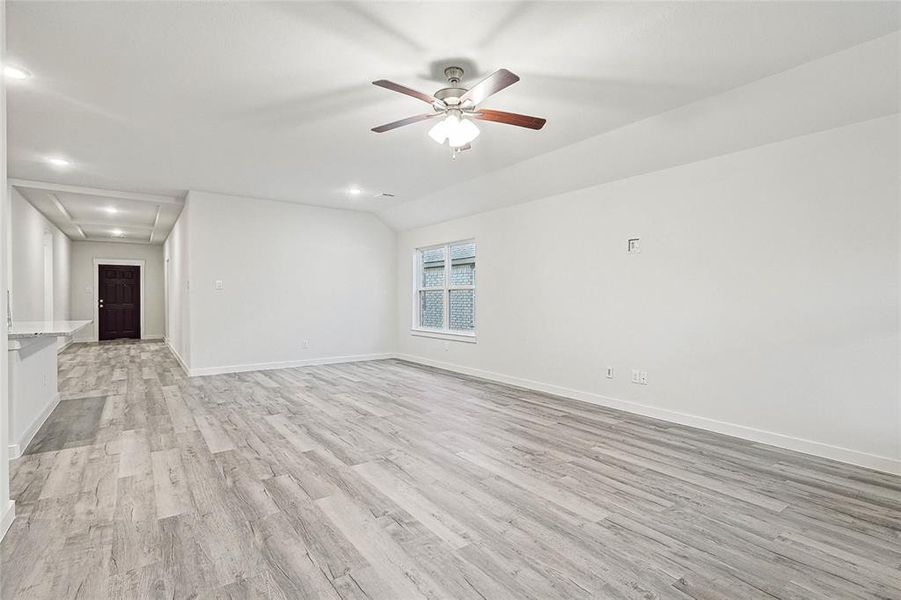 Unfurnished living room featuring light hardwood / wood-style flooring, lofted ceiling, and ceiling fan