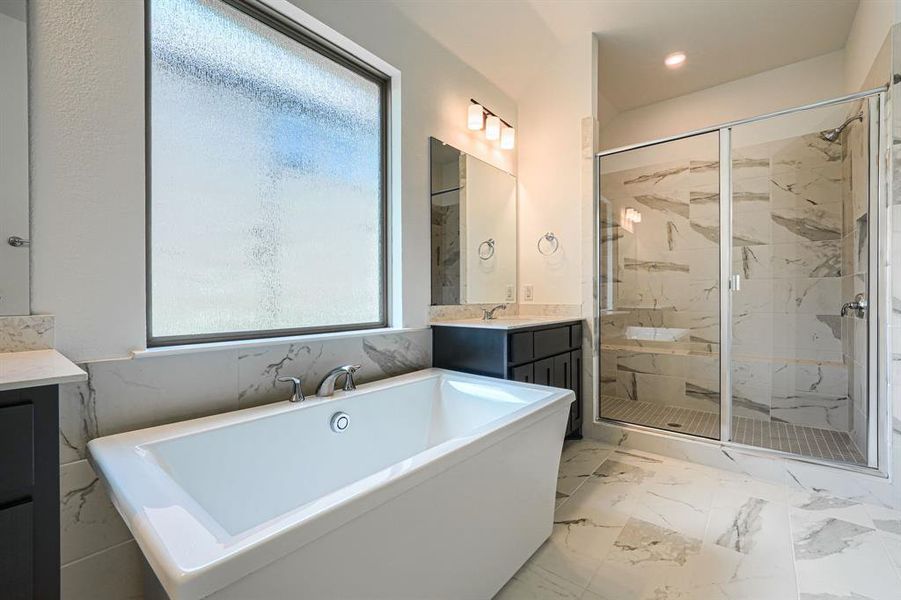Bathroom with vanity with extensive cabinet space, separate shower and tub, tile flooring, and tile walls
