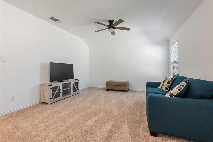 Living room featuring ceiling fan, carpet flooring, and vaulted ceiling