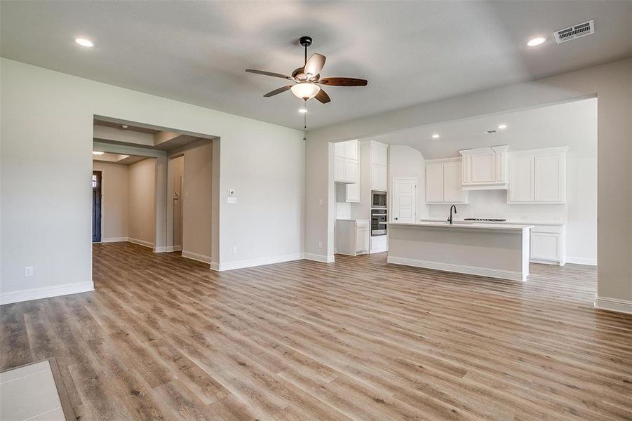 Unfurnished living room featuring sink, ceiling fan, and light hardwood / wood-style floors