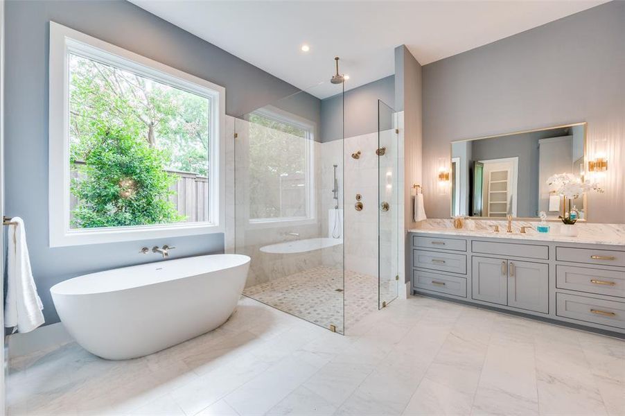Bathroom with a wealth of natural light, vanity, plus walk in shower, and tile patterned floors