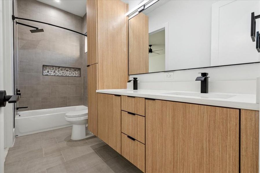 Full bathroom featuring ceiling fan, vanity, tiled shower / bath combo, tile patterned floors, and toilet