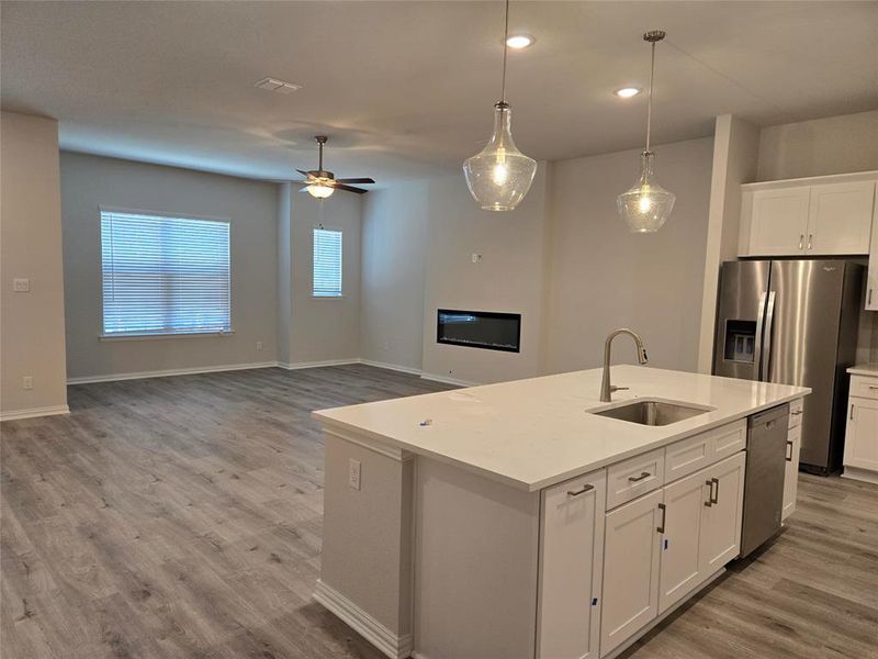 Kitchen with sink, decorative light fixtures, a center island with sink, white cabinetry, and appliances with stainless steel finishes