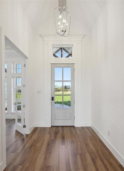 Foyer featuring dark hardwood / wood-style flooring, a notable chandelier, and vaulted ceiling