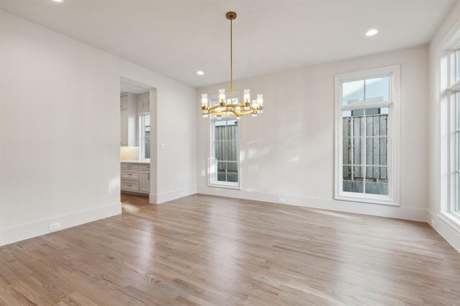 Unfurnished dining area with light hardwood / wood-style floors and an inviting chandelier