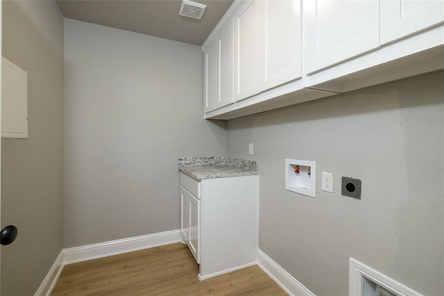 Laundry room with hookup for a washing machine, cabinets, light hardwood / wood-style flooring, and hookup for an electric dryer