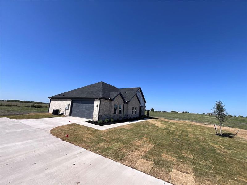 View of front of property with cooling unit, a front yard, and a garage