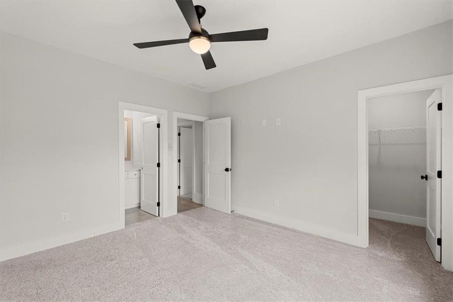 Unfurnished bedroom featuring ceiling fan, light carpet, a closet, and a spacious closet