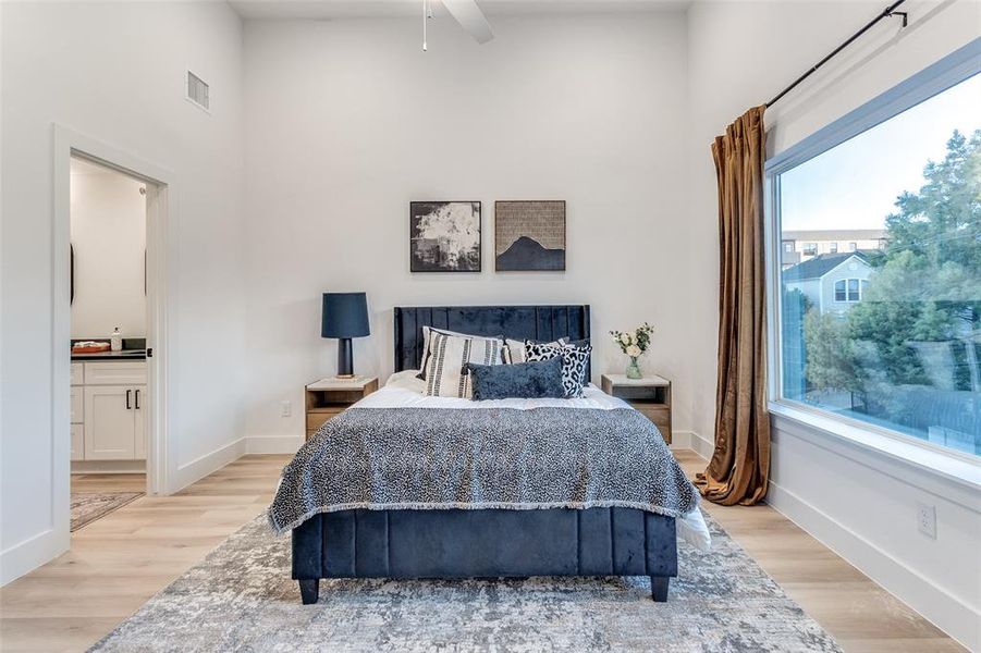 Bedroom featuring ceiling fan, ensuite bathroom, and light hardwood / wood-style floors