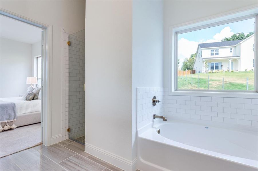 Bathroom featuring a wealth of natural light and separate shower and tub