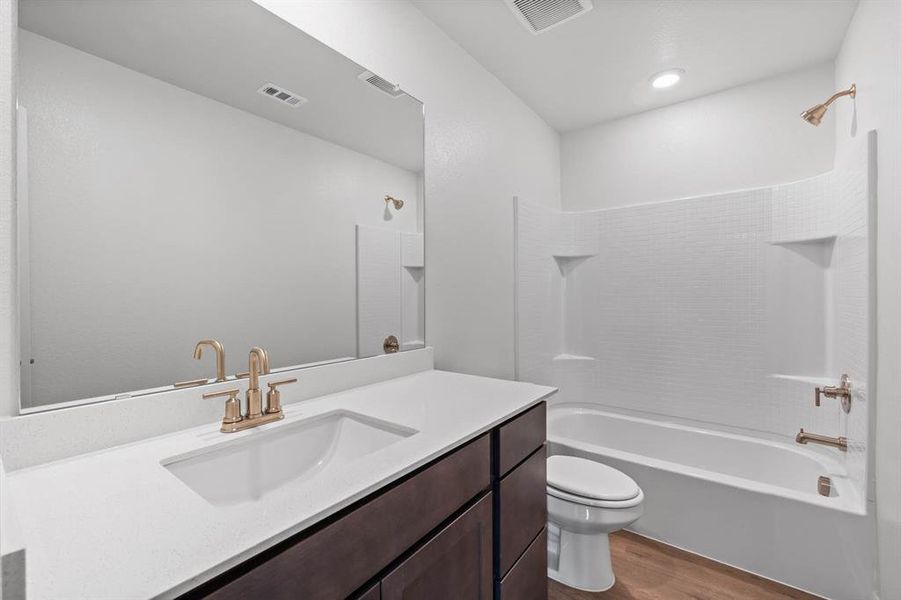 Full bathroom with wood-type flooring, vanity, shower / bath combination, and toilet