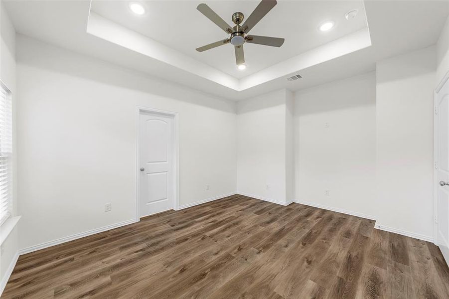 Unfurnished room with dark wood-type flooring, ceiling fan, and a raised ceiling