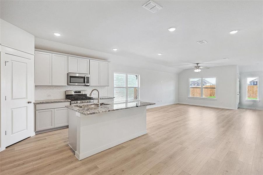 Kitchen with appliances with stainless steel finishes, tasteful backsplash, light hardwood / wood-style flooring, and a wealth of natural light