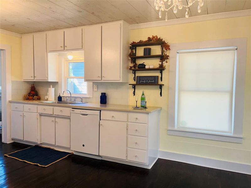 Kitchen with dishwasher, dark hardwood / wood-style floors, backsplash, sink, and white cabinetry