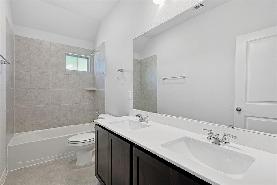 Full bathroom with tile patterned floors, toilet, tiled shower / bath, and dual bowl vanity