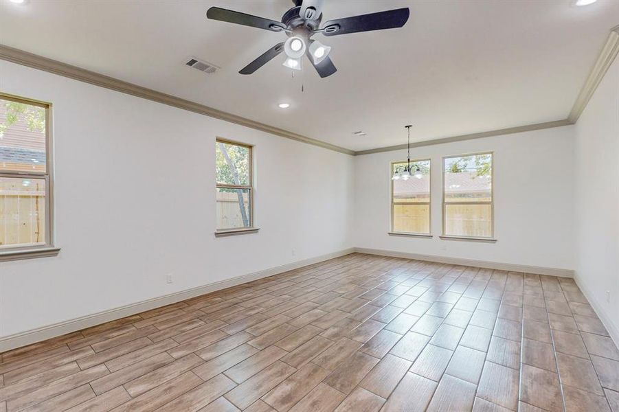 Unfurnished room with ceiling fan with notable chandelier, crown molding, and a wealth of natural light