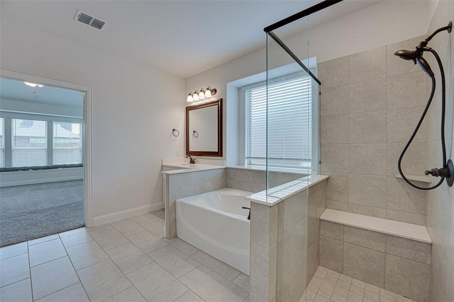 Bathroom with vanity, independent shower and bath, tile patterned flooring, and a healthy amount of sunlight