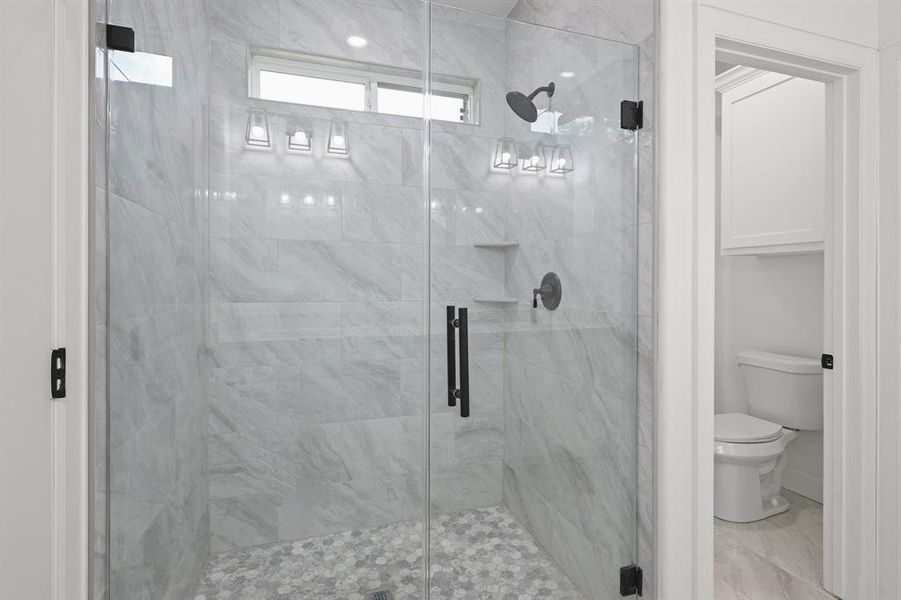 Bathroom featuring a shower with shower door and toilet