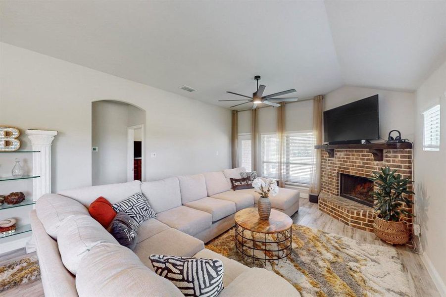 Living room with a fireplace, ceiling fan, lofted ceiling, and light hardwood / wood-style floors