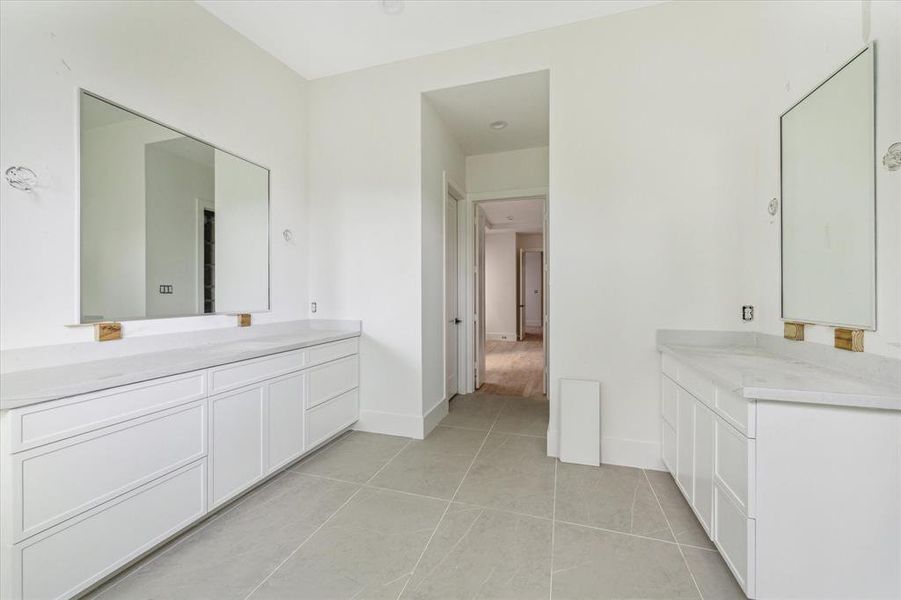 A stunning primary suite with his and her dedicated vanity area, custom cabinets, detailed tile work and more.