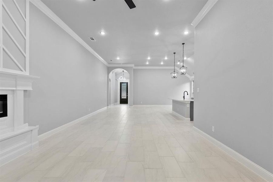 Unfurnished living room featuring ceiling fan and ornamental molding