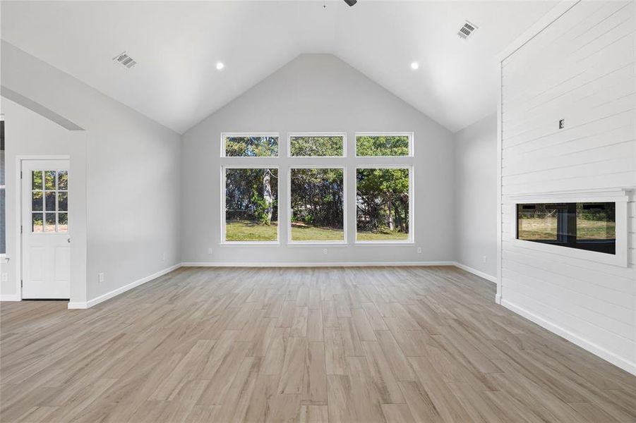 The Living Room Features A Vaulted Ceiling & Wall Of Windows Framing A Beautiful View