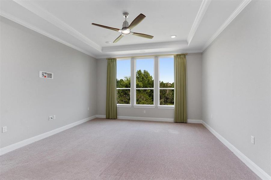 primary bedroom w/ high tray ceiling and ceiling fan