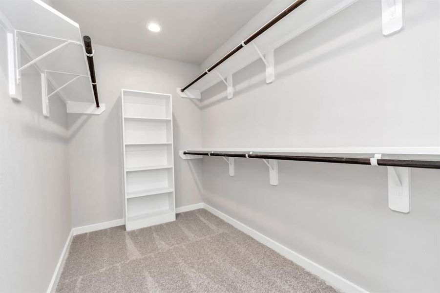 Immerse yourself in the lap of luxury within this roomy walk-in closet boasting high ceilings, built in shelves, and plush carpeting. Sample photo of completed home with similar floor plan. As-built interior colors and selections may vary.