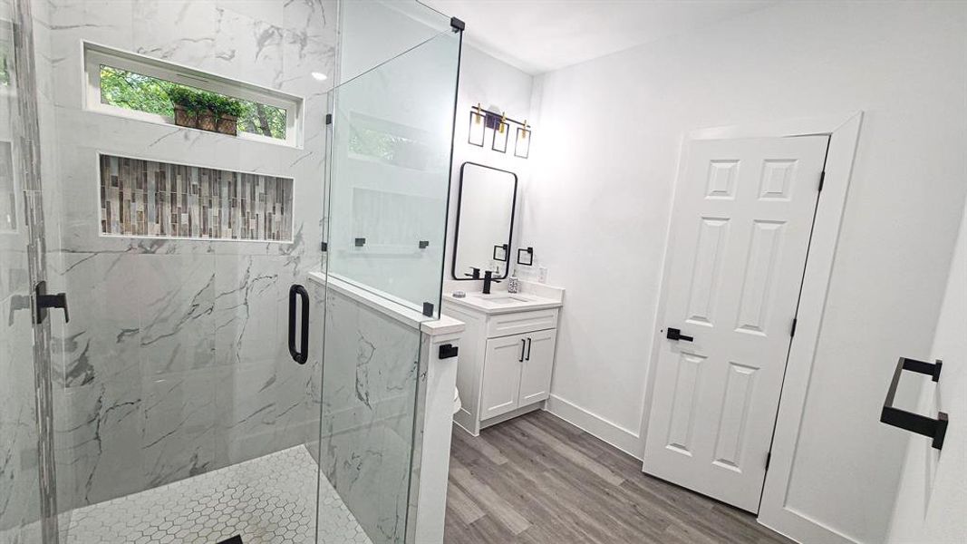 Bathroom featuring vanity, hardwood / wood-style floors, and a shower with door