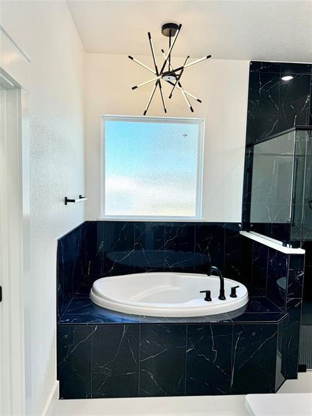 Bathroom featuring a healthy amount of sunlight, a chandelier, and separate shower and tub